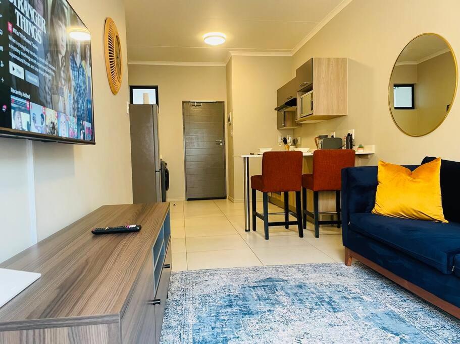 a living room with a blue couch and a kitchen at Mikeys Place on Lever with Fibre Uncapped WiFi in Midrand