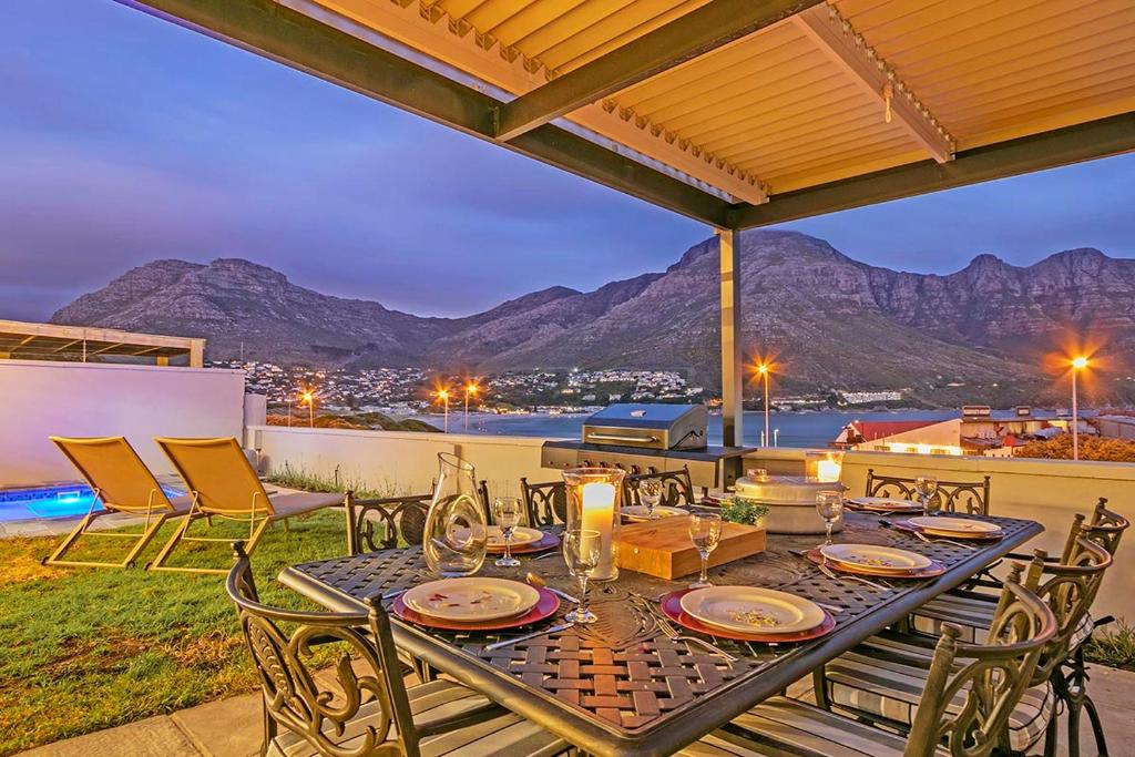 une table sur une terrasse avec vue sur les montagnes dans l'établissement Villa de la Mer Hout Bay Beachfront, au Cap
