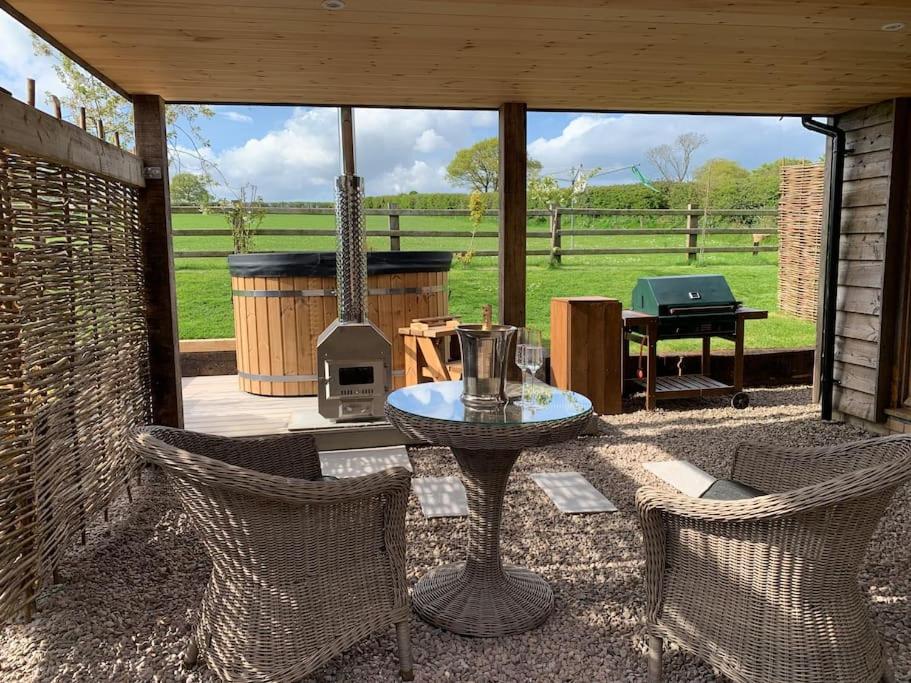 a patio with a table and chairs and a grill at Wood Fired Hot Tub & Pergola with Glass Balcony. in Brecon