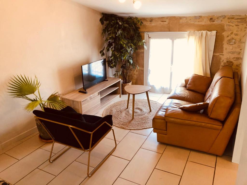 a living room with a couch and a television at Appartement sur le toit avec terrasse et belle vue in Roujan