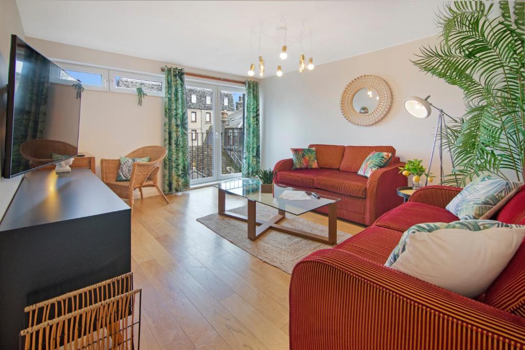 een woonkamer met een rode bank en een tafel bij Mearns Street Apartments - Grampian Lettings Ltd in Aberdeen