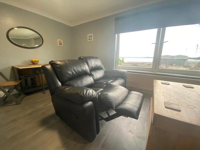 a living room with a leather reclining chair and a mirror at Burnt Island 2 bed apartment with stunning views in Fife