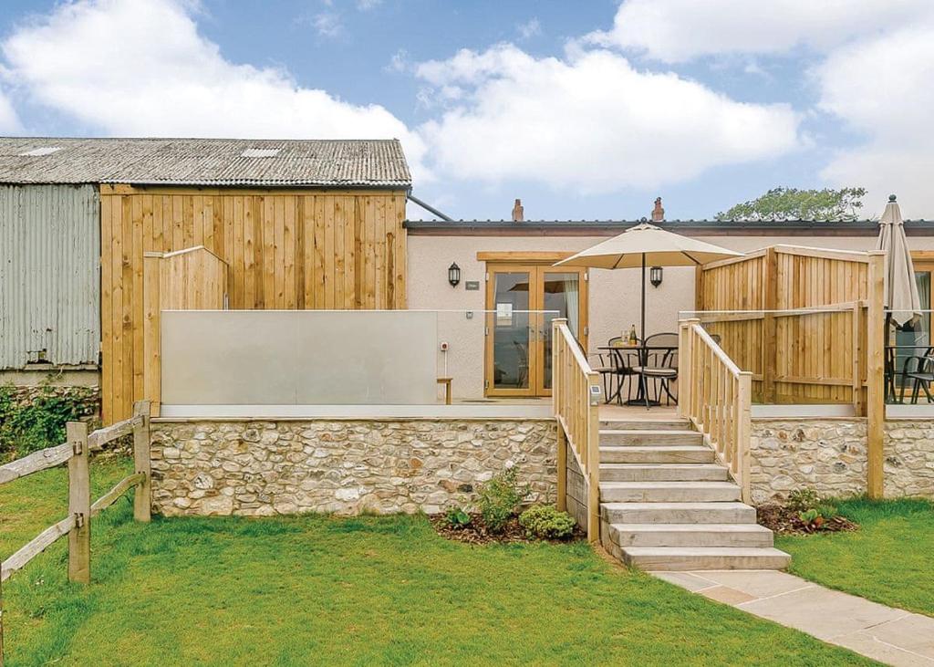 a house with a stone retaining wall and a patio at Larkshayes Cottages in Hawley Bottom