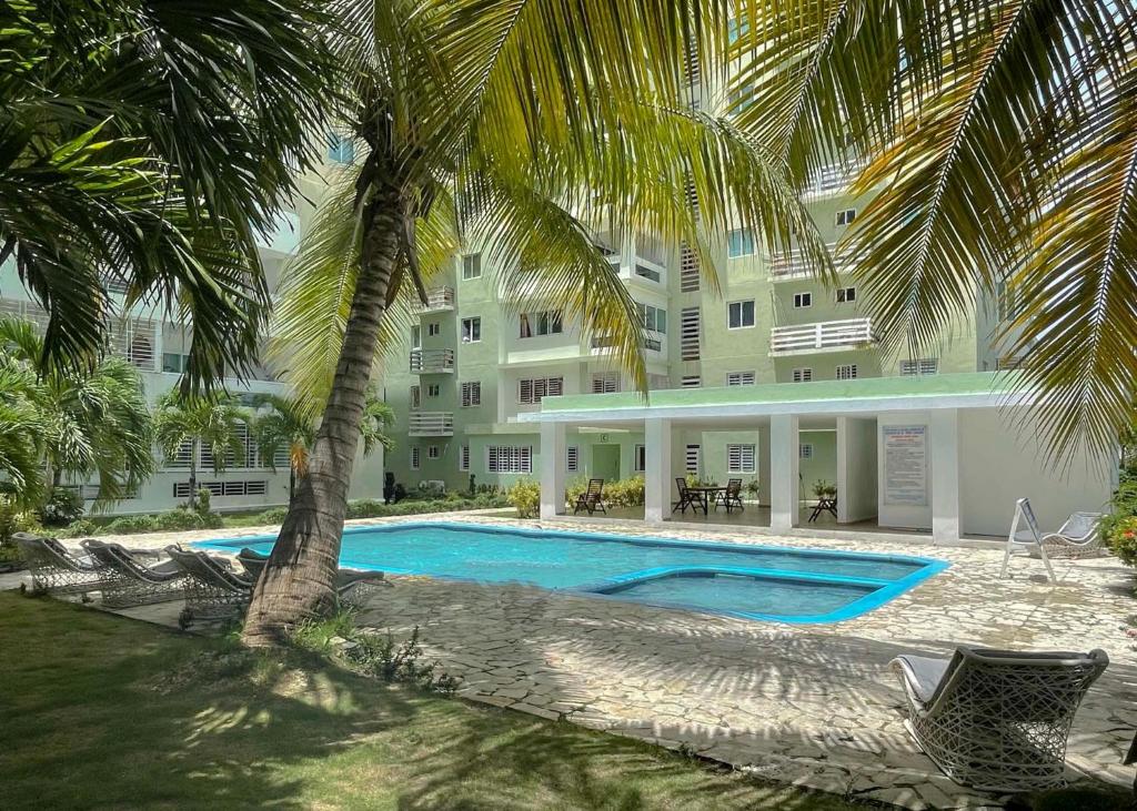 a swimming pool in front of a building with palm trees at Escape Oceanfront Condo in Avenida Espana w/Pool in Santo Domingo