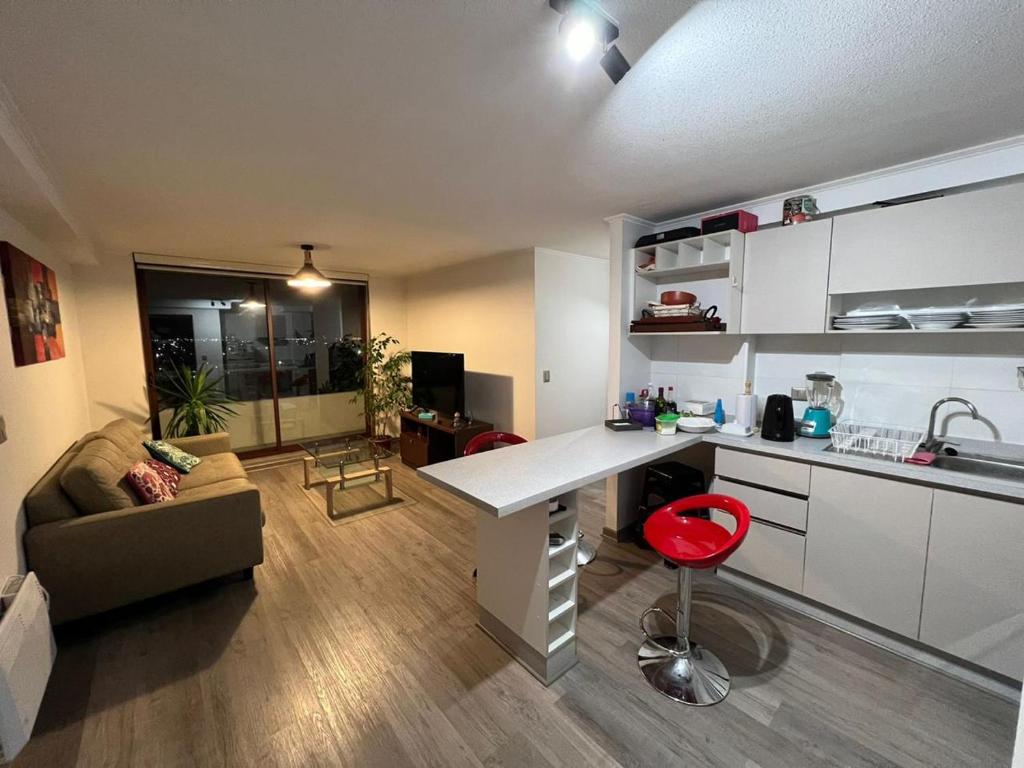 uma cozinha e sala de estar com uma secretária e um sofá em Departamento amoblado Chillán Centro em Chillán