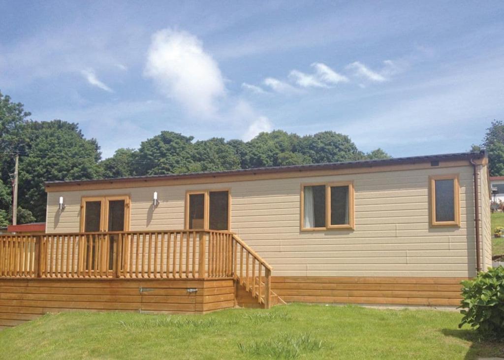 a mobile home with a deck on a lawn at Llwyngwair Manor Holiday Park in Nevern