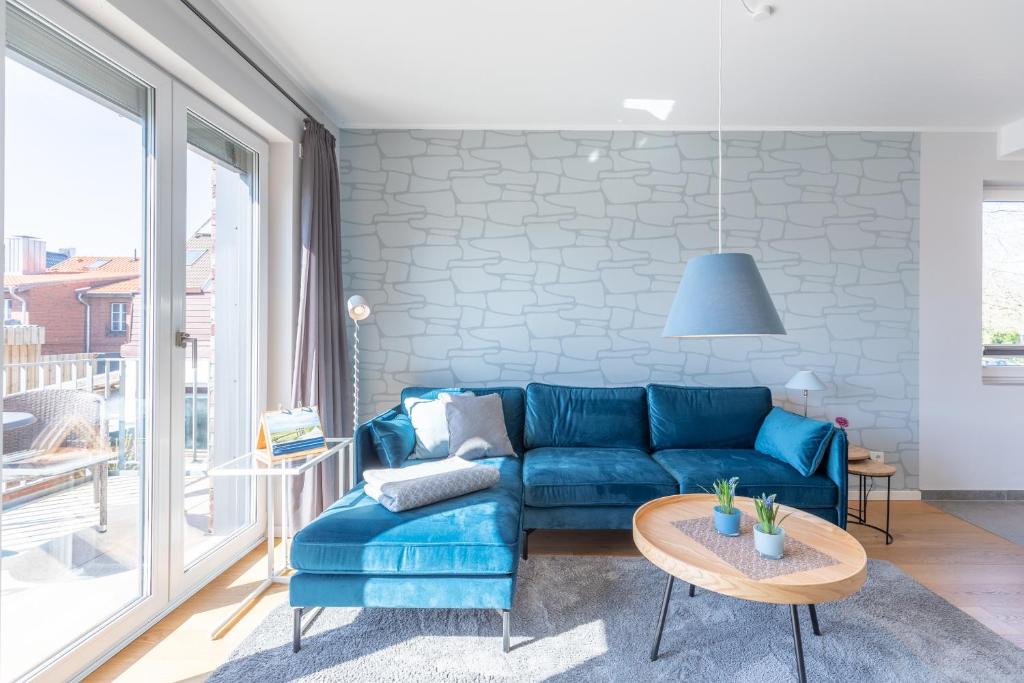 a living room with a blue couch and a table at Ankerzeit in Husum
