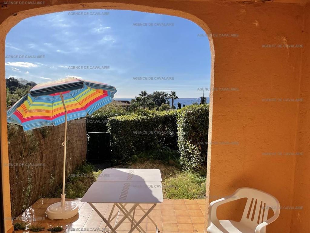 einen Tisch mit einem Sonnenschirm und einem Stuhl auf einer Terrasse in der Unterkunft Rez-de-jardin T2 avec terrasse et parking - FR-1-100-284 in Rayol-Canadel-sur-Mer