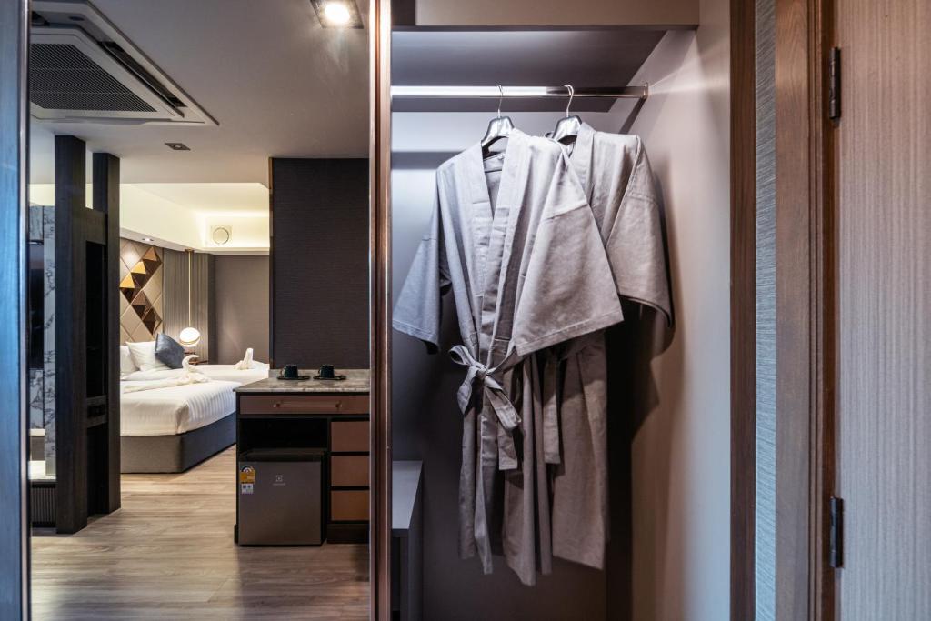 An open wardrobe area with robes, a minibar and a glimpse of the bedroom.