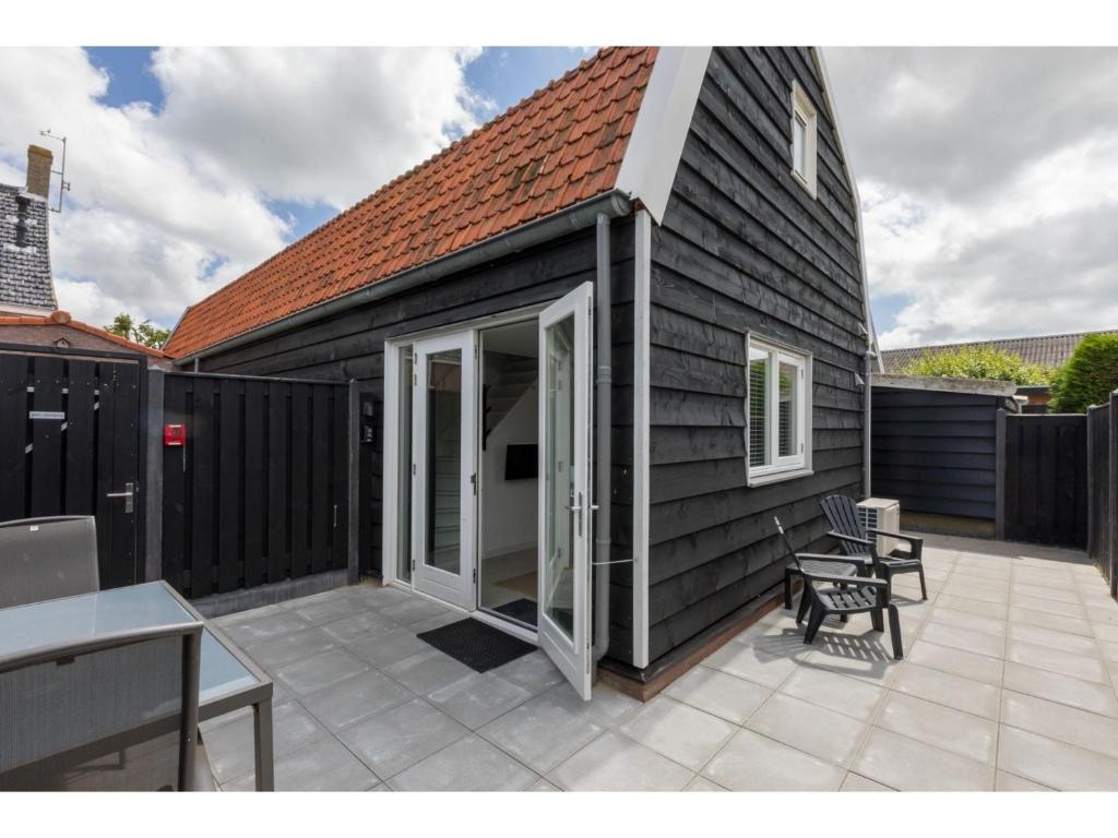 BiggekerkeにあるHoliday Home in Biggekerke with Infrared Saunaのスライド式ガラスドア付きのパティオが備わるブラックハウスです。