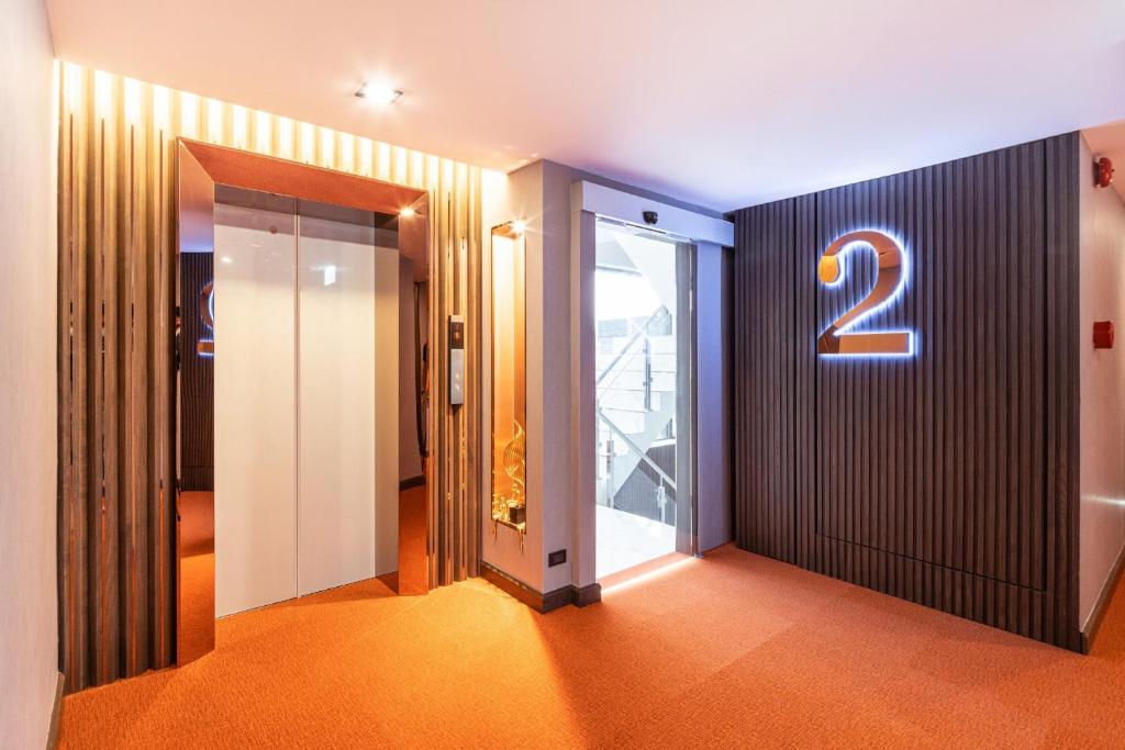A warmly lit second-floor elevator lobby with a large illuminated number 2.