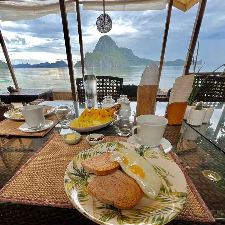 a plate of eggs and bread on a table with a view of the ocean at Golden Monkey Beach Hotel in El Nido
