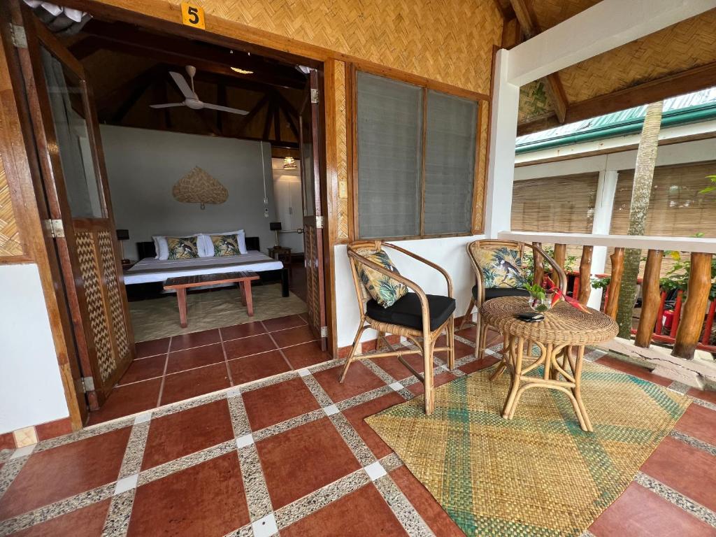 a room with a balcony with a bed and a table at Golden Monkey Beach Hotel in El Nido