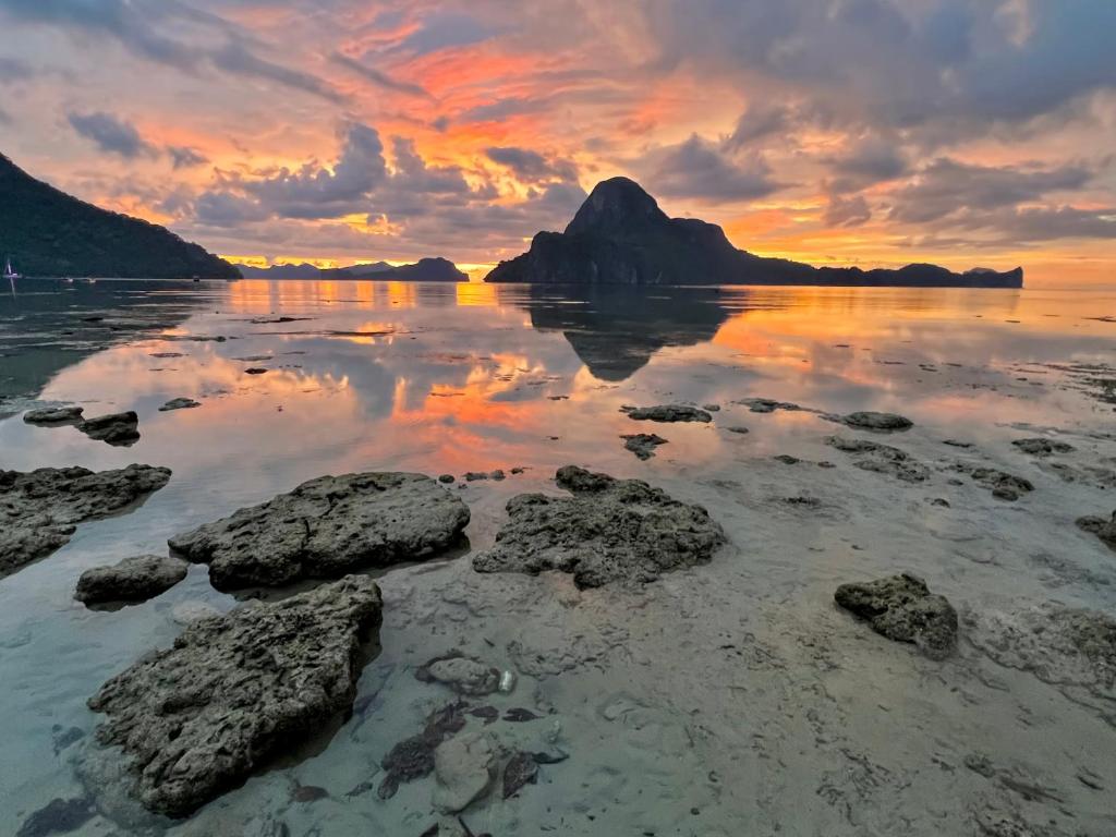 a sunset over a body of water with rocks at Golden Monkey Beach Hotel in El Nido