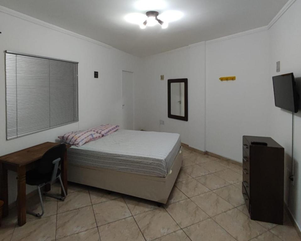 um quarto com uma cama, uma secretária e uma televisão em Casa Privativa Metrô Penha em São Paulo