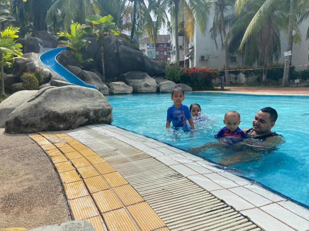 a man and two children in a swimming pool at SMILEz HOMESTAY B109 AT PD PERDANA CONDO RESORT in Port Dickson