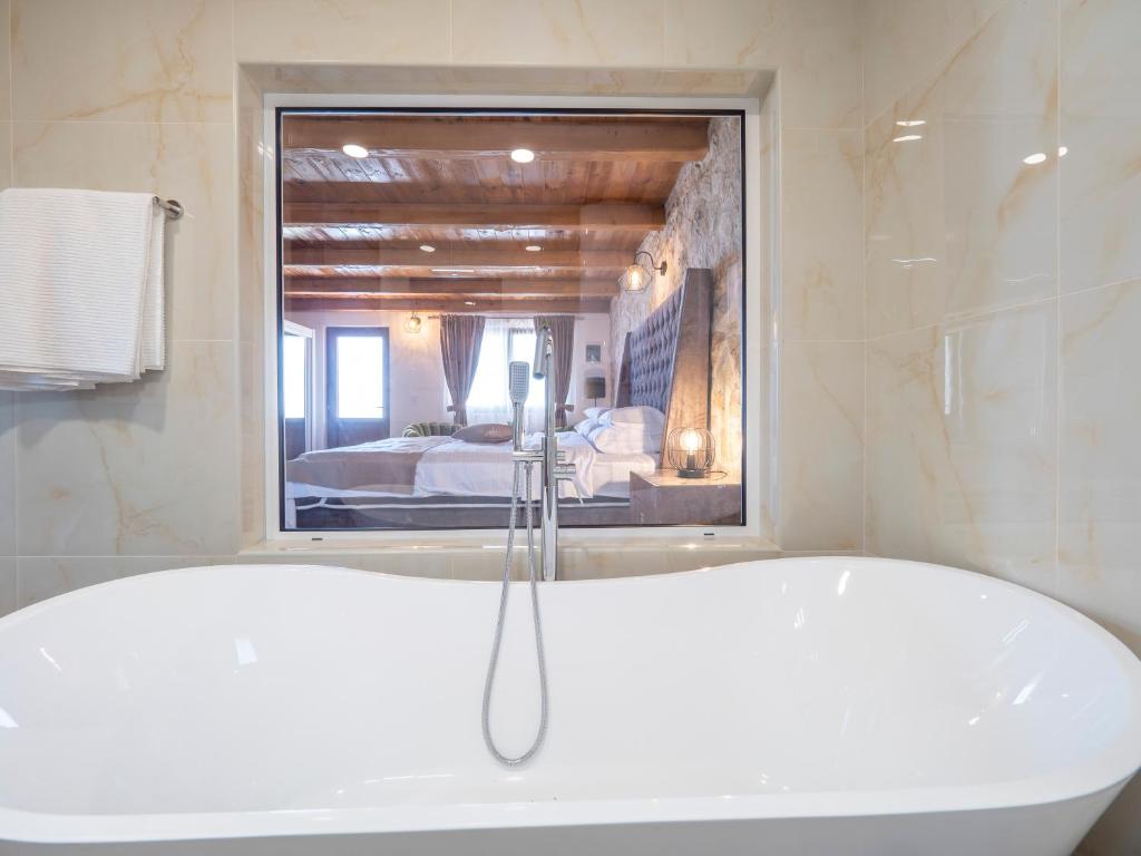 a bath tub in a bathroom with a bedroom at Harmonia Bungalows & Pool in Sveti Stefan
