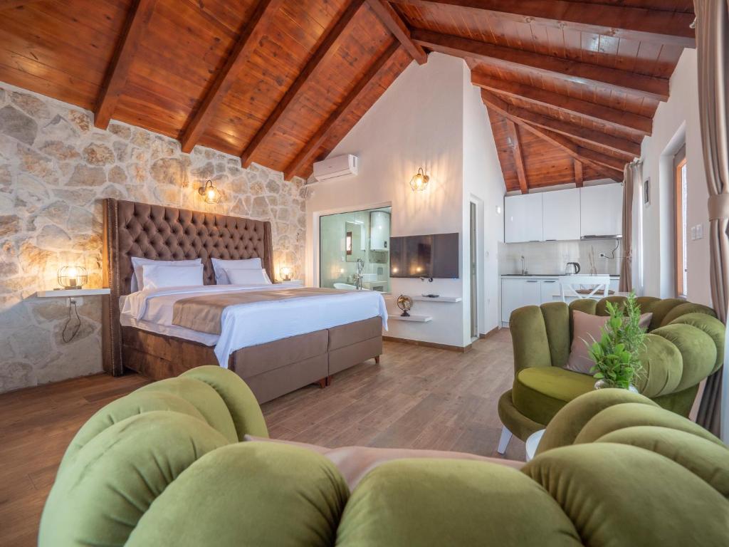 a bedroom with a bed and two green chairs at Harmonia Bungalows & Pool in Sveti Stefan