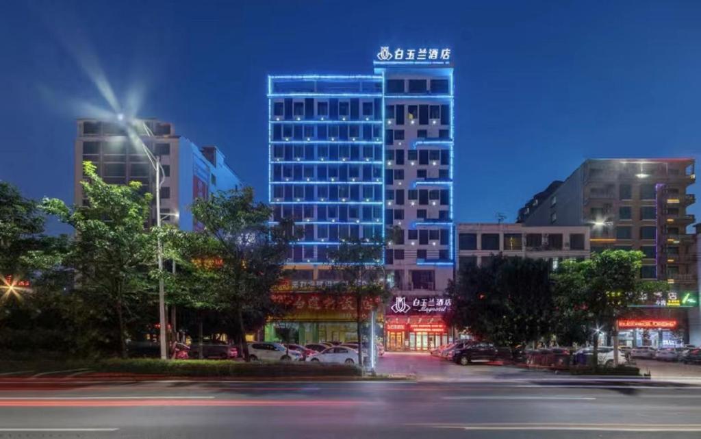 a tall building with a sign on top of it at Jinjiang Magnolia Haikou Chengmai Software Park Hotel in Haikou