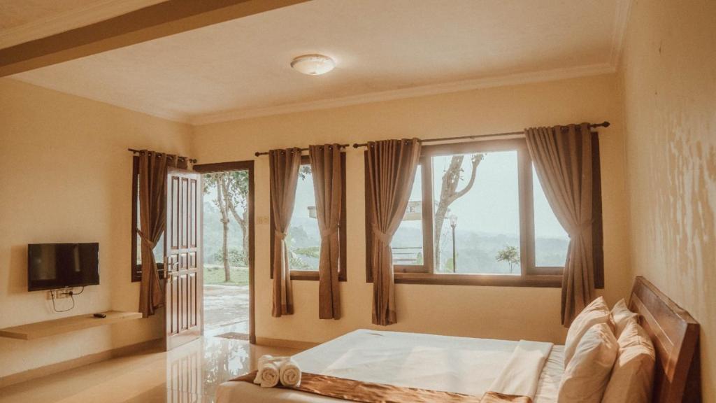 a bedroom with a bed and a large window at Blessing Hills Family Resort & Hotel in Mojokerto