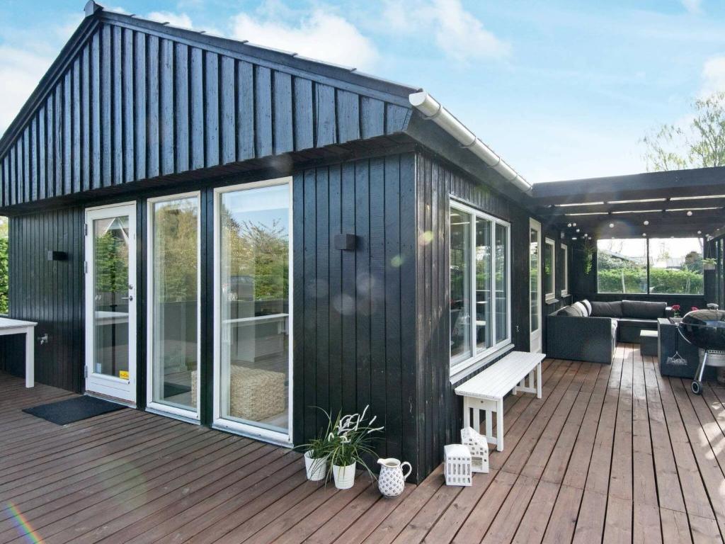 een zwart huis met een terras met een bank bij 6 person holiday home in Odder in Odder