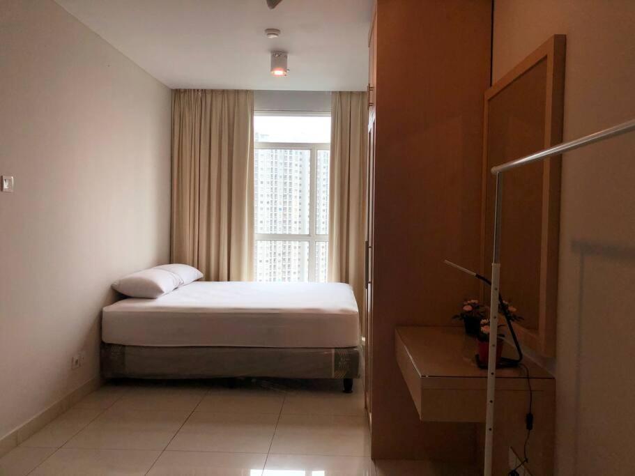 a bedroom with a bed in front of a window at Central Park Residences (2BR - 22nd Floor) in Jakarta