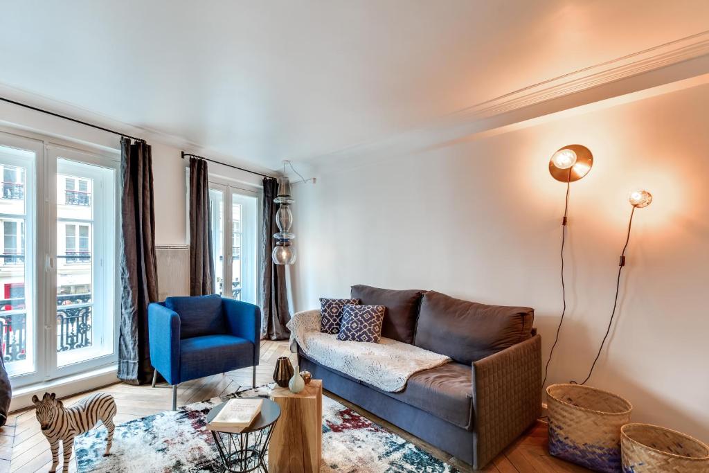 ein Wohnzimmer mit einem Sofa und einem blauen Stuhl in der Unterkunft Sweet Inn - Etienne Marcel in Paris