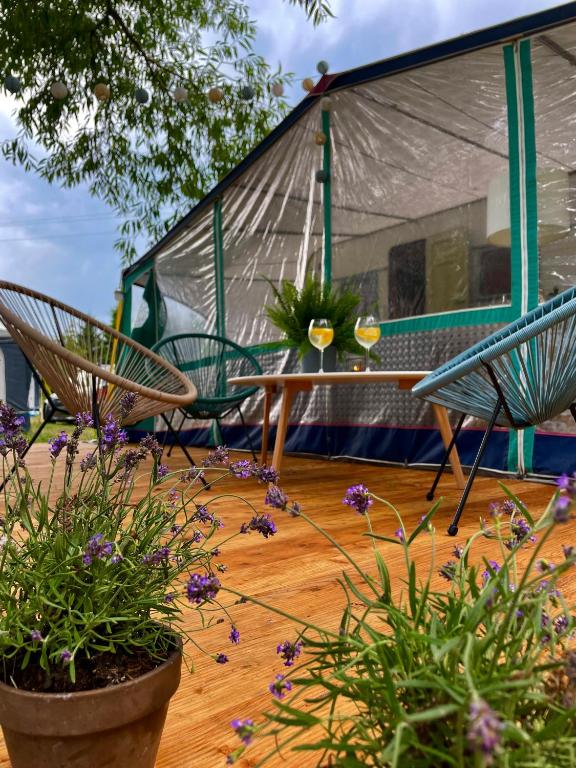 a tent and two chairs and flowers on a deck at Słoneczne Przyczepy Dębki in Dębki