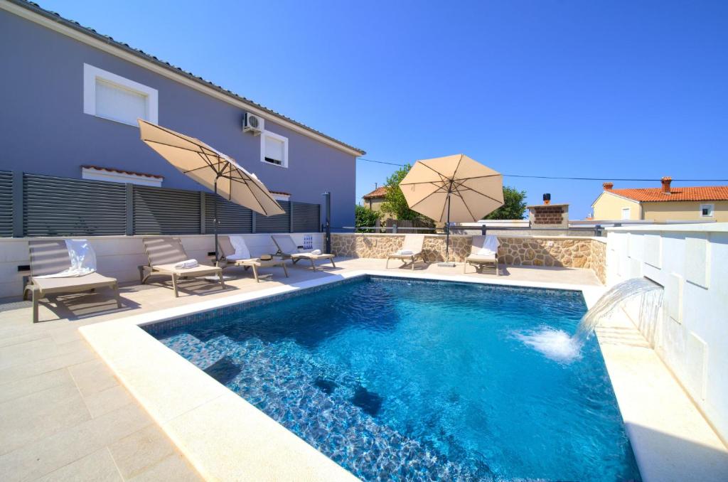 basen z leżakami i parasolami obok domu w obiekcie Villa QUARNARO with heated pool w mieście Omišalj