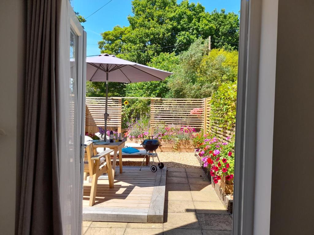 an open door to a patio with an umbrella at Forest Palms Studio The New Forest National Park in Fordingbridge