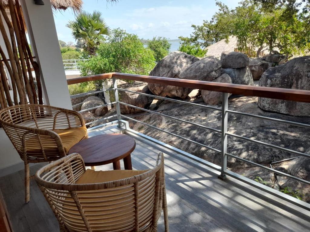 a balcony with chairs and a view of rocks at Oruwa Boutique Villas in Arugam Bay