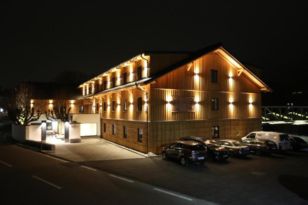 un edificio con coches estacionados en un estacionamiento por la noche en Hotel Wildschütz Basic, en Altmünster