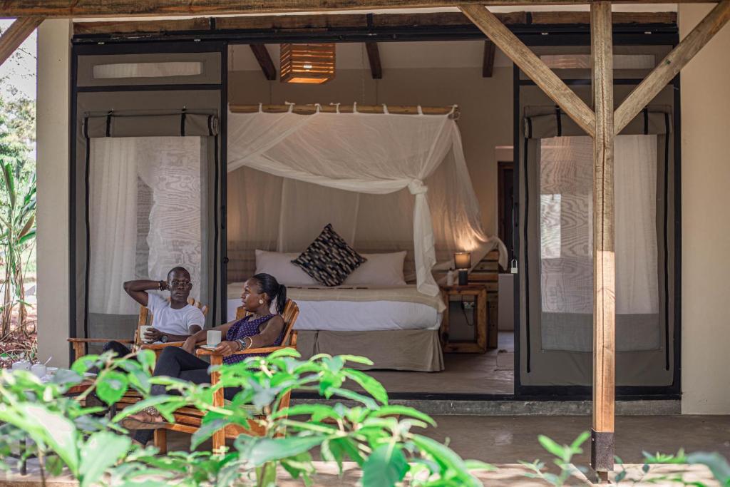 twee vrouwen in een stoel in een slaapkamer bij Adrift River Club in Kangulumira