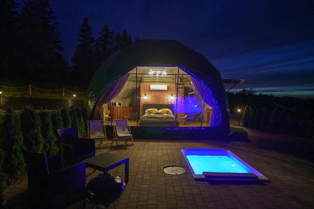 a tent with a bed and a swimming pool at night at Peak Glamp in Zakopane