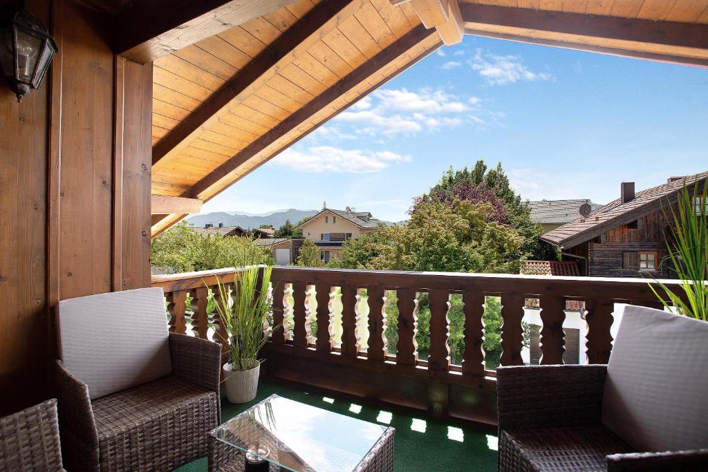 eine Veranda mit Stühlen und einem Tisch auf dem Balkon in der Unterkunft Josys Ferienwohnung in Gstadt am Chiemsee