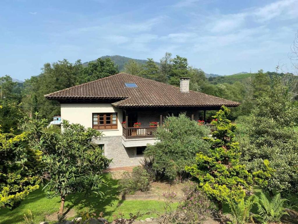 a house with a balcony in the middle of trees at Casa de Los Carpinteros in Arriondas