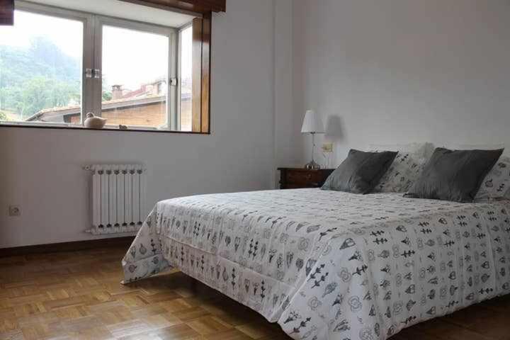 1 dormitorio con 1 cama con edredón blanco y ventana en Amplio y luminoso apartamento en Villaviciosa en Villaviciosa