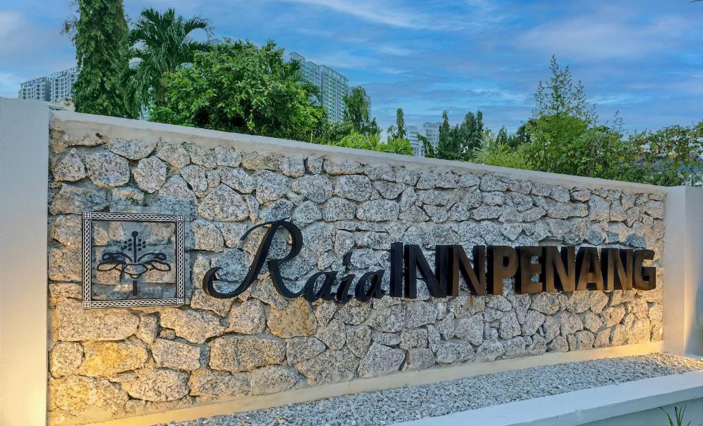 una pared de retención de piedra con una señal en ella en Raia Inn Penang en Bayan Lepas