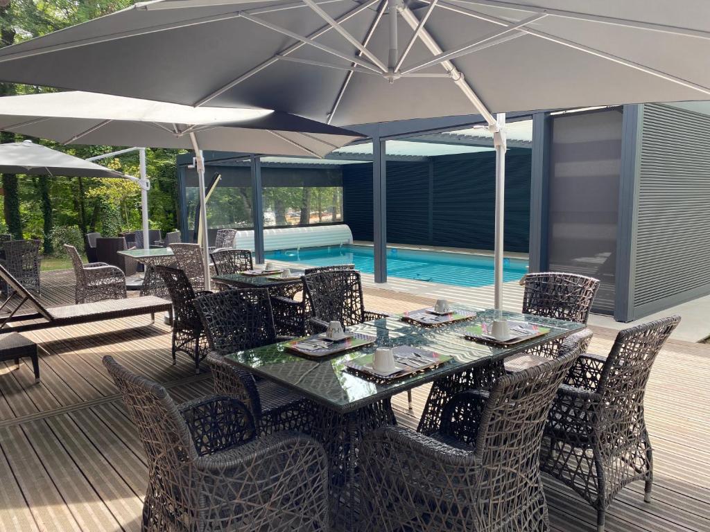 patio con tavolo, sedie e ombrellone di Enzo Hôtels Diane - Logis Amnéville ad Amnéville