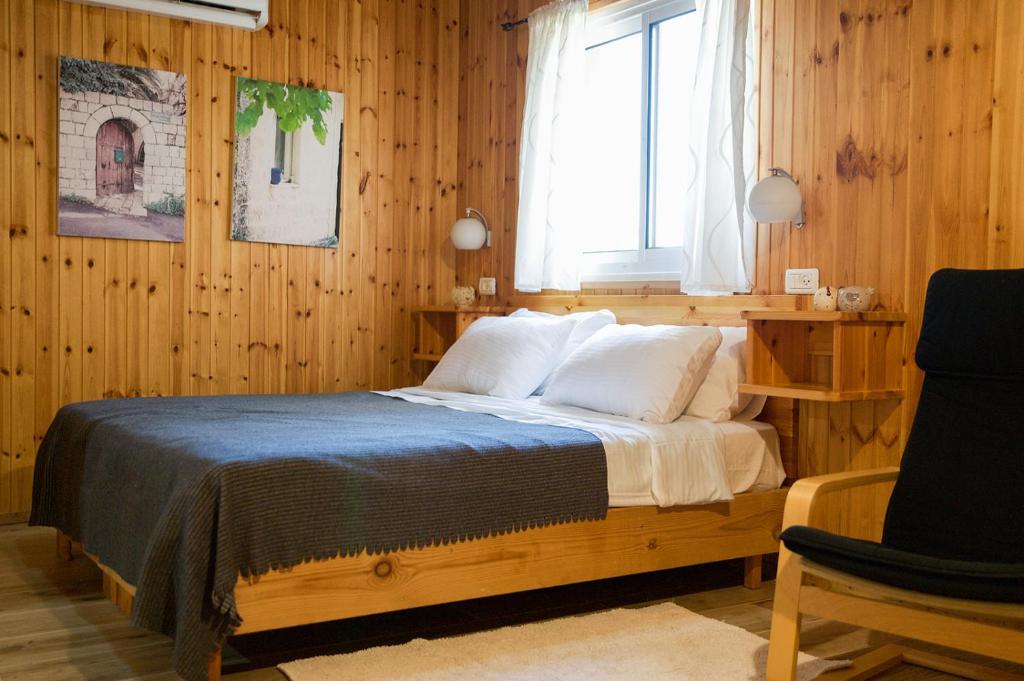 a bedroom with a bed with wooden walls and a window at Naomi's place הבית של נעמי in Moshav Ramot