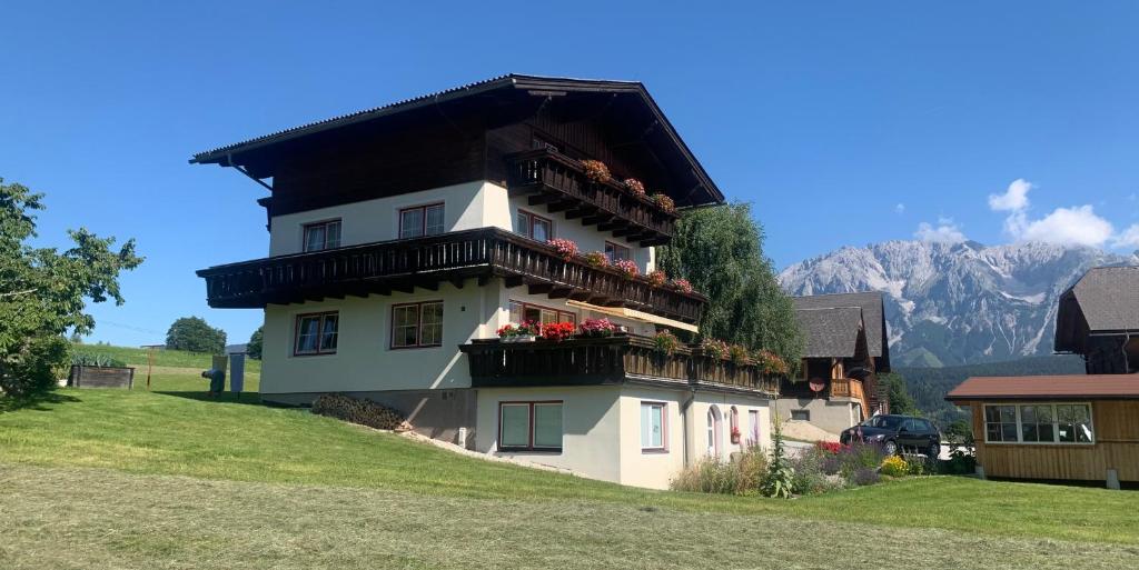 ein Haus mit Blumen auf den Balkonen auf einem Hügel in der Unterkunft Frühstückspension Erika in Schladming