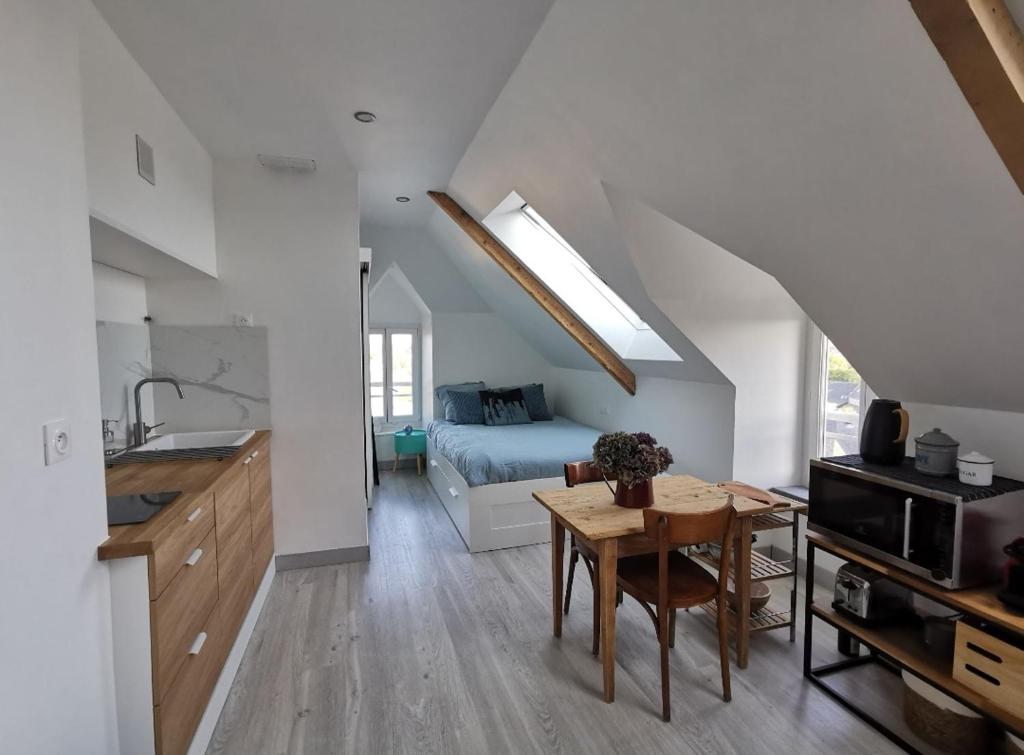 a kitchen and living room with a table and a bed at Studio cosy au bord de mer in Lancieux