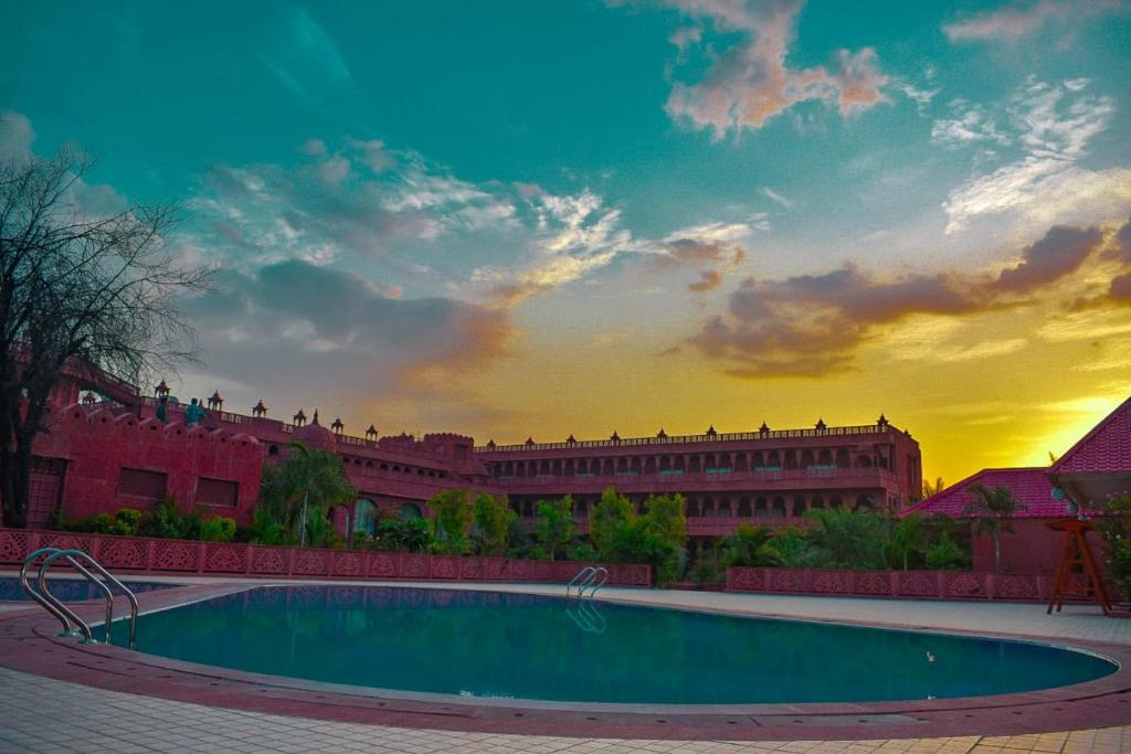 uma piscina em frente a um edifício com um pôr-do-sol em Puratan Qila em Sawai Madhopur