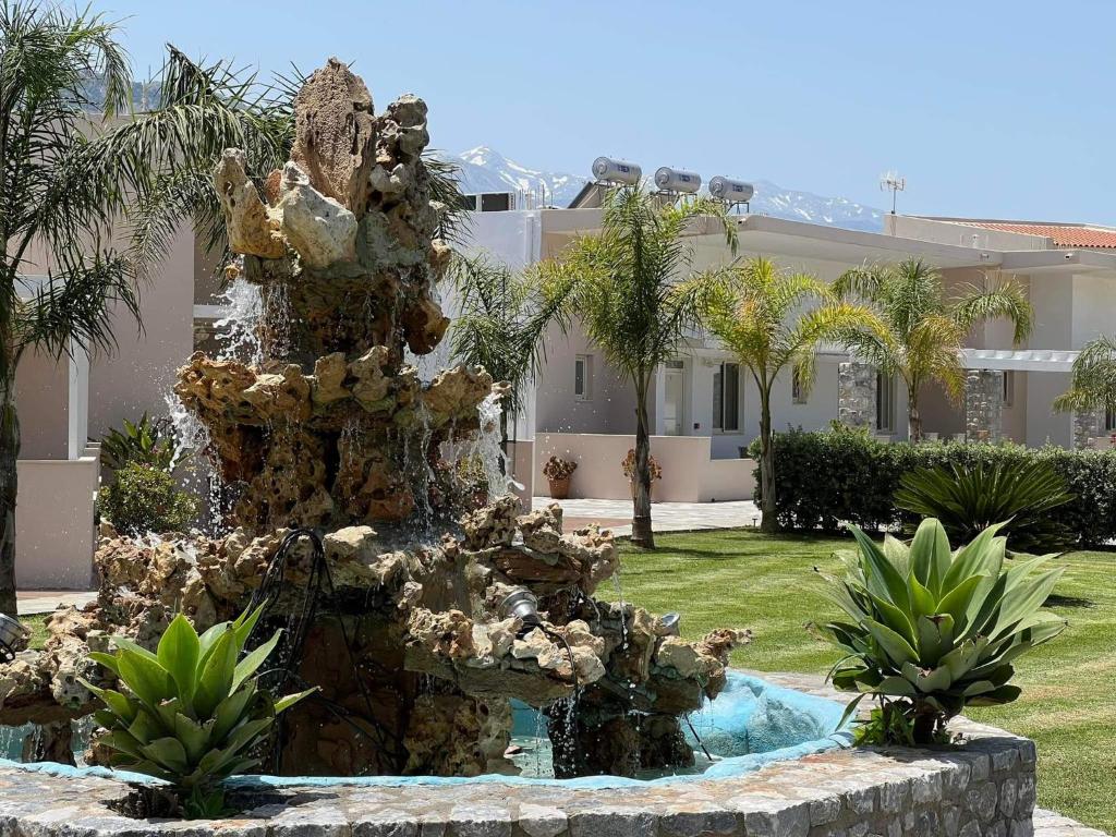a fountain in front of a house with palm trees at Argiri Apartments & Suites in Georgioupolis