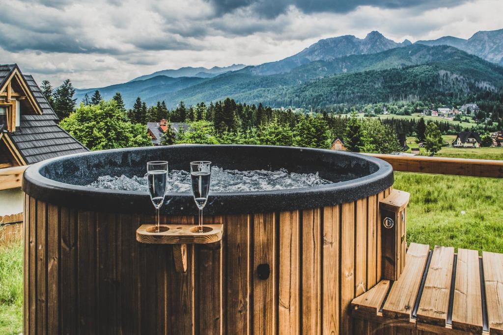 een hot tub met 2 wijnglazen op een terras bij Osada Szeligówka - Premium Chalets Kościelisko in Kościelisko