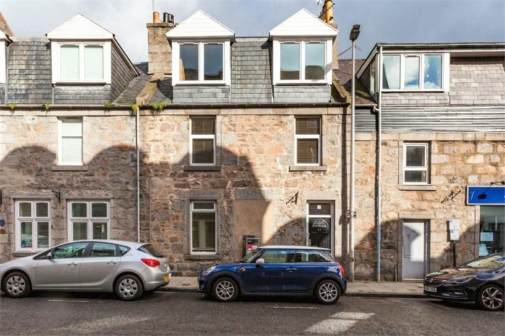 two cars parked in front of a brick building at Chapel Street 42B First floor 1-bedroom apartment, Aberdeen city center in Aberdeen