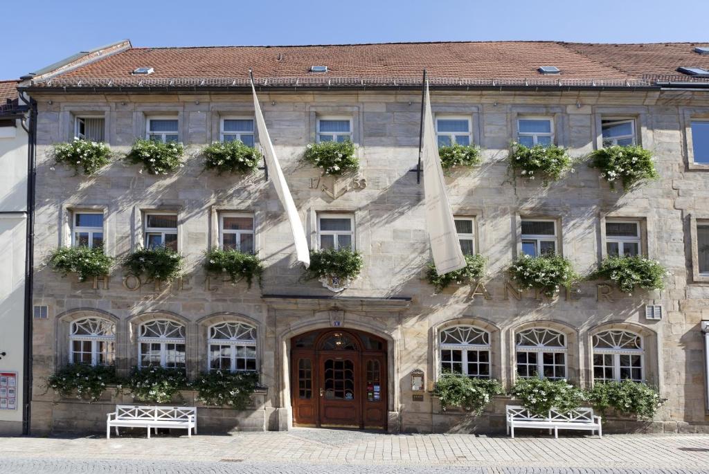 ein großes Steingebäude mit zwei Flaggen davor in der Unterkunft Hotel Goldener Anker in Bayreuth