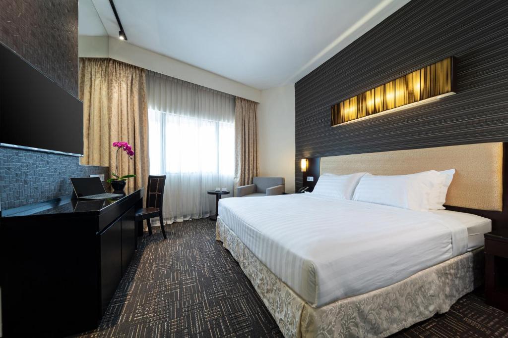 a hotel room with a bed and a desk at Hotel Royal Queens in Singapore