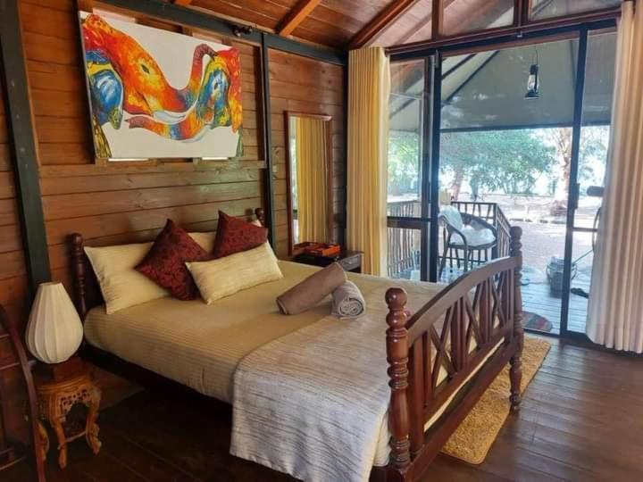 a bedroom with a bed and a large window at Kaaya Eco Resort Yala in Tissamaharama