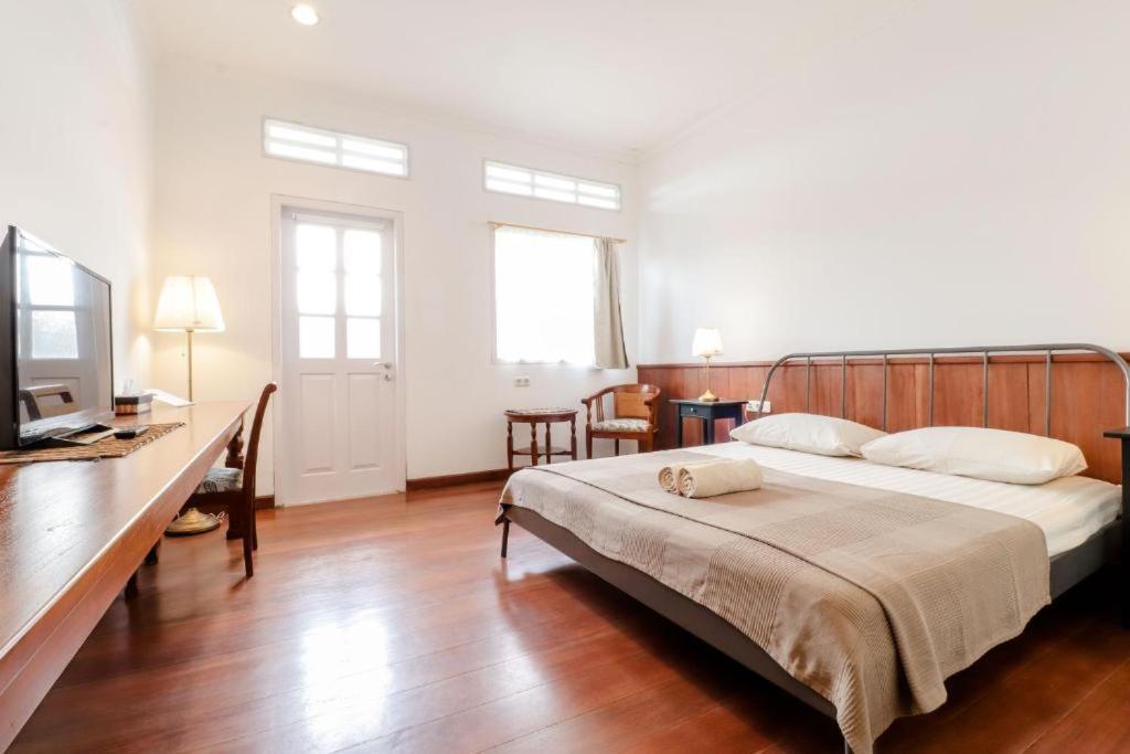 a bedroom with a bed and a desk with a television at Palem Kipas Homestay in Yogyakarta